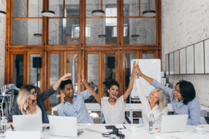 An office team high-fiving each other, showing how cultural fit matters