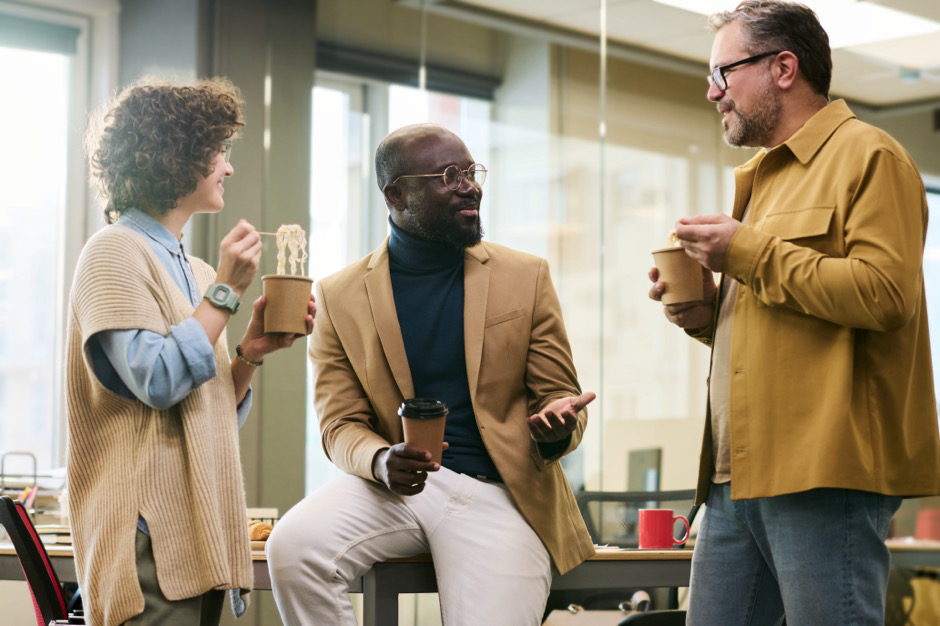 A team leader smiles as he communicates with his team in an office setting.