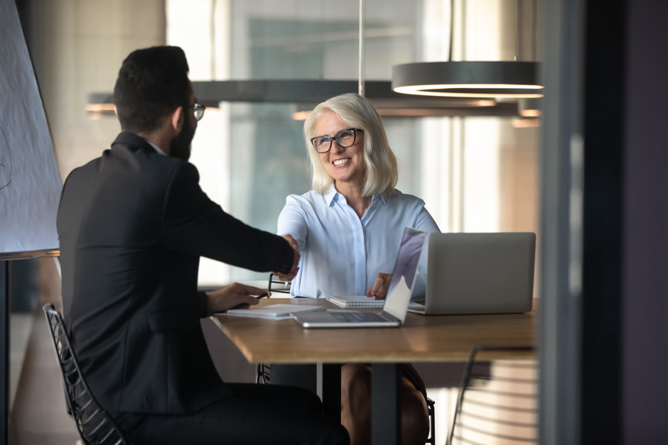 a man and a woman shake hands at the beginning of a job interview