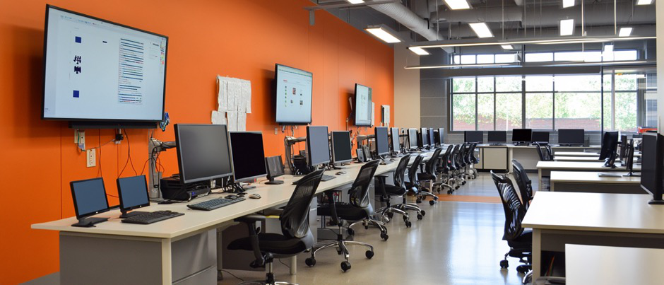 An empty training room with chairs, desks, and computers.