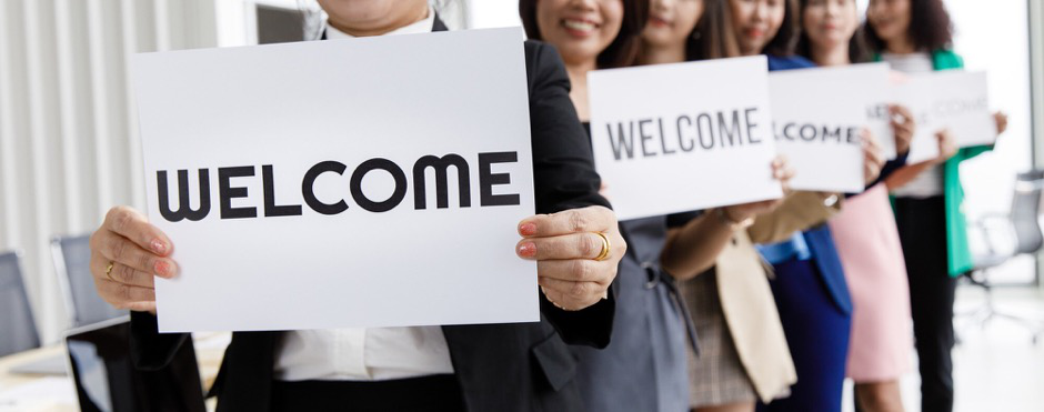 A row of team members holding welcome signs