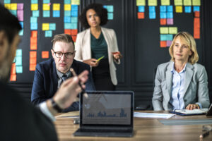 change management team sitting around a table with a black board behind them with colorful post-it notes